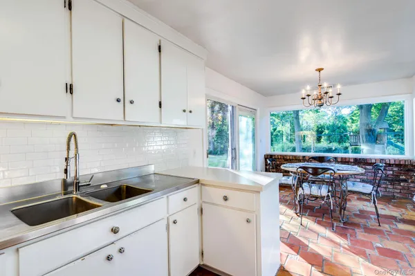 a kitchen with stainless steel appliances a sink a stove and white cabinets with wooden floor
