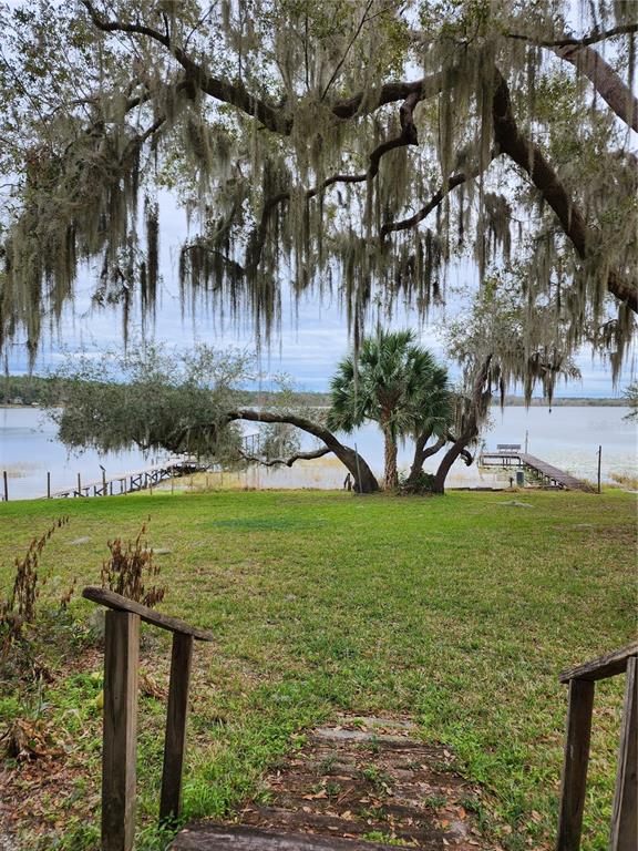 a view of a lake with a yard and large trees