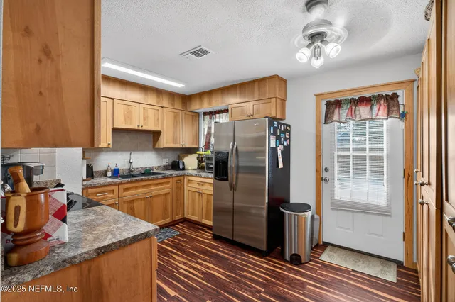 a kitchen with stainless steel appliances granite countertop a refrigerator a sink dishwasher a stove and a dining table with wooden floor