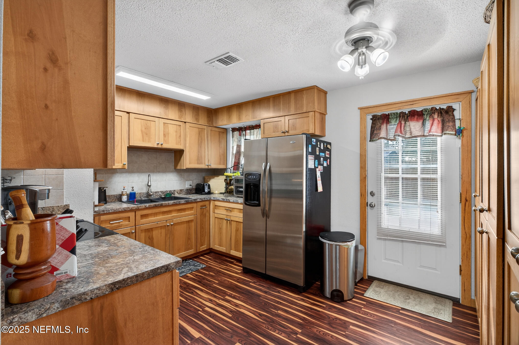 44108 Becker Avenue Callahan, FL 32011 - Photo 5 of 28 a kitchen with stainless steel appliances granite countertop a refrigerator a sink dishwasher a stove and a dining table with wooden floor