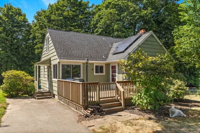 a view of a house with a yard plants and large tree