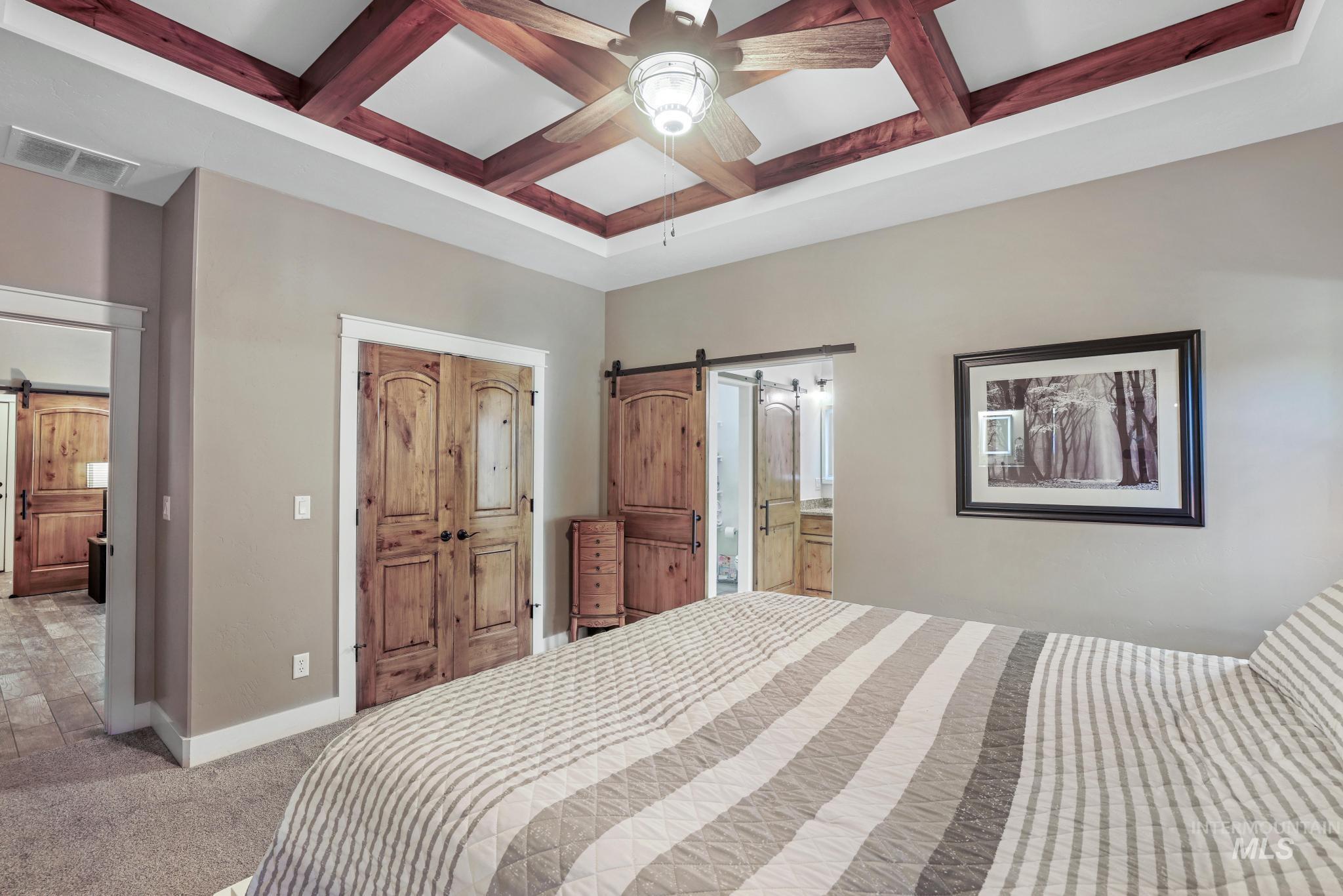 2043 Prospector Way Twin Falls, ID 83301 - Photo 17 of 29 Bedroom featuring a barn door, coffered ceiling, beamed ceiling, carpet floors, and a closet