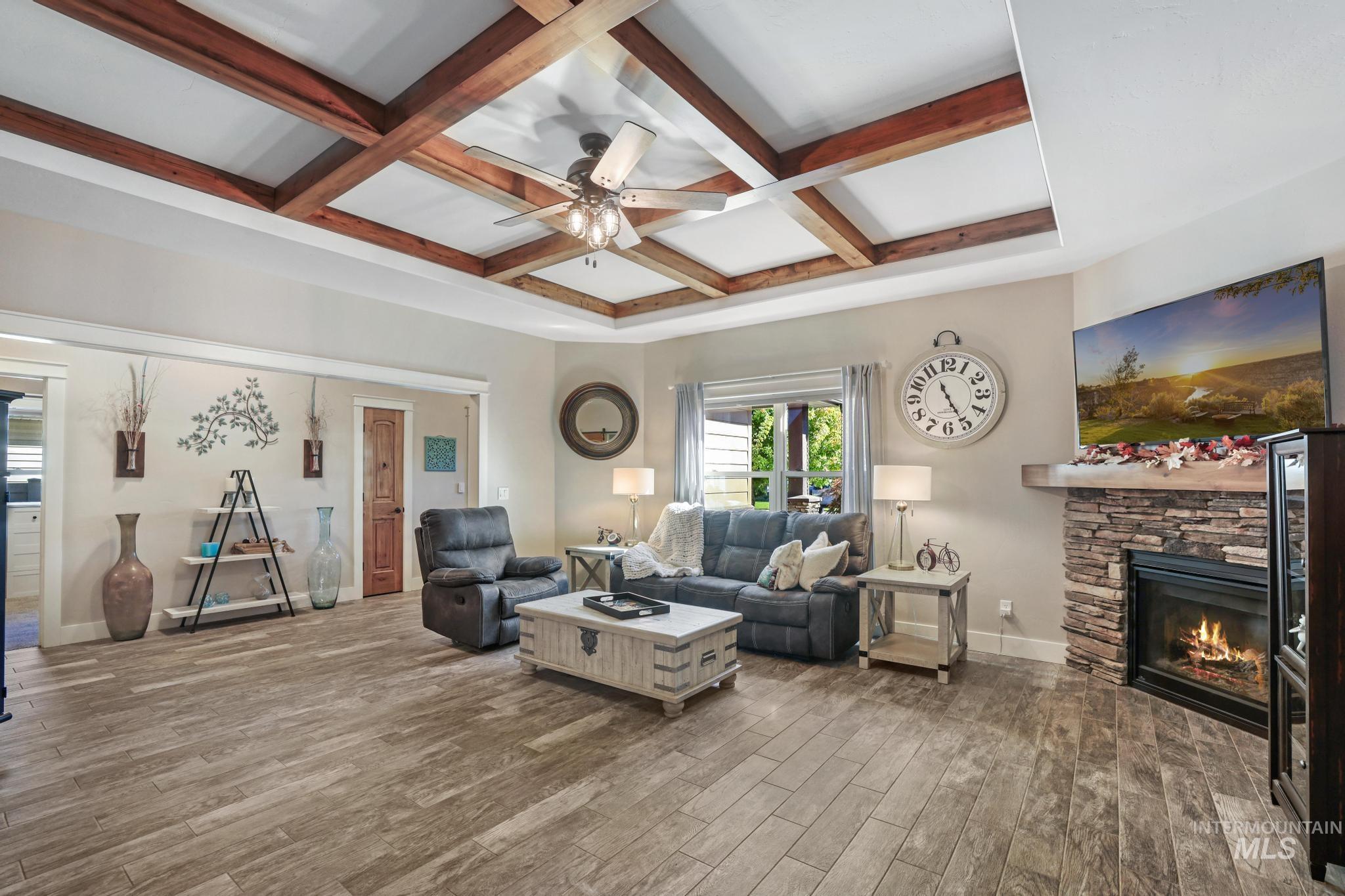 2043 Prospector Way Twin Falls, ID 83301 - Photo 3 of 29 Living area featuring coffered ceiling, beamed ceiling, wood finished floors, ceiling fan, and a stone fireplace