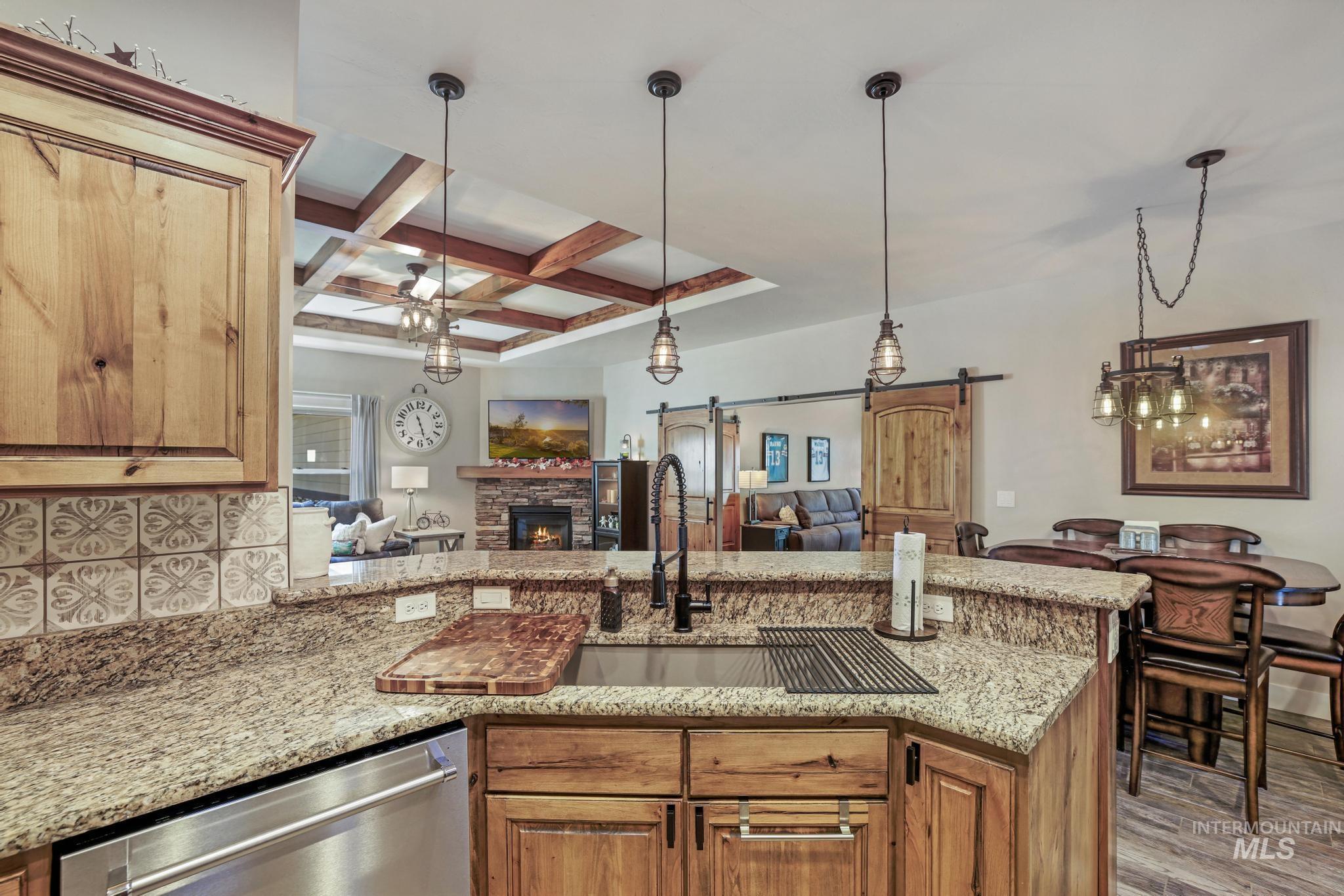 2043 Prospector Way Twin Falls, ID 83301 - Photo 6 of 29 Kitchen with a barn door, coffered ceiling, hanging light fixtures, a peninsula, and light stone counters