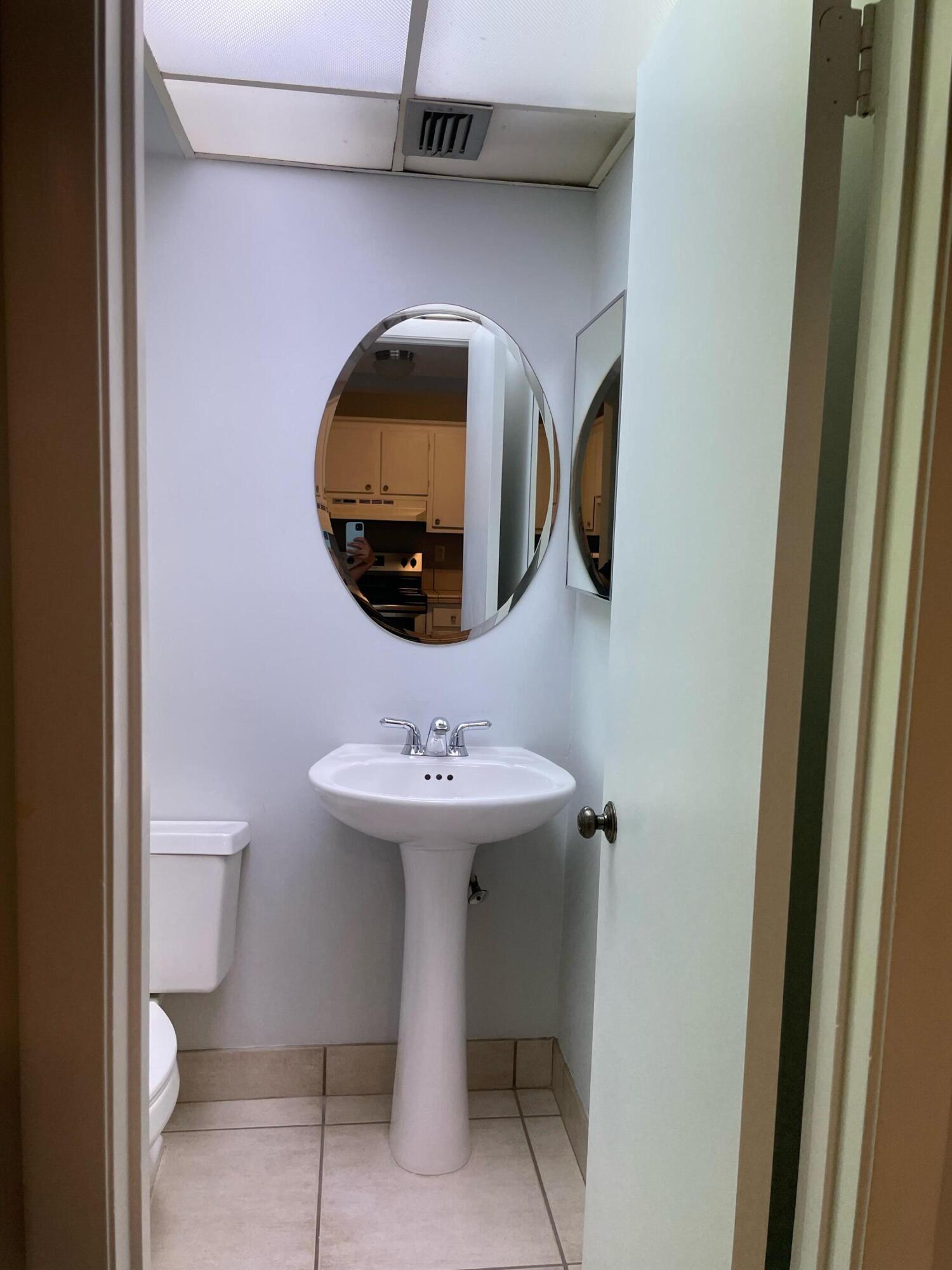 9440 Southwest 8th Street, Unit 217 Boca Raton, FL 33428 - Photo 13 of 28 a bathroom with a toilet sink and mirror