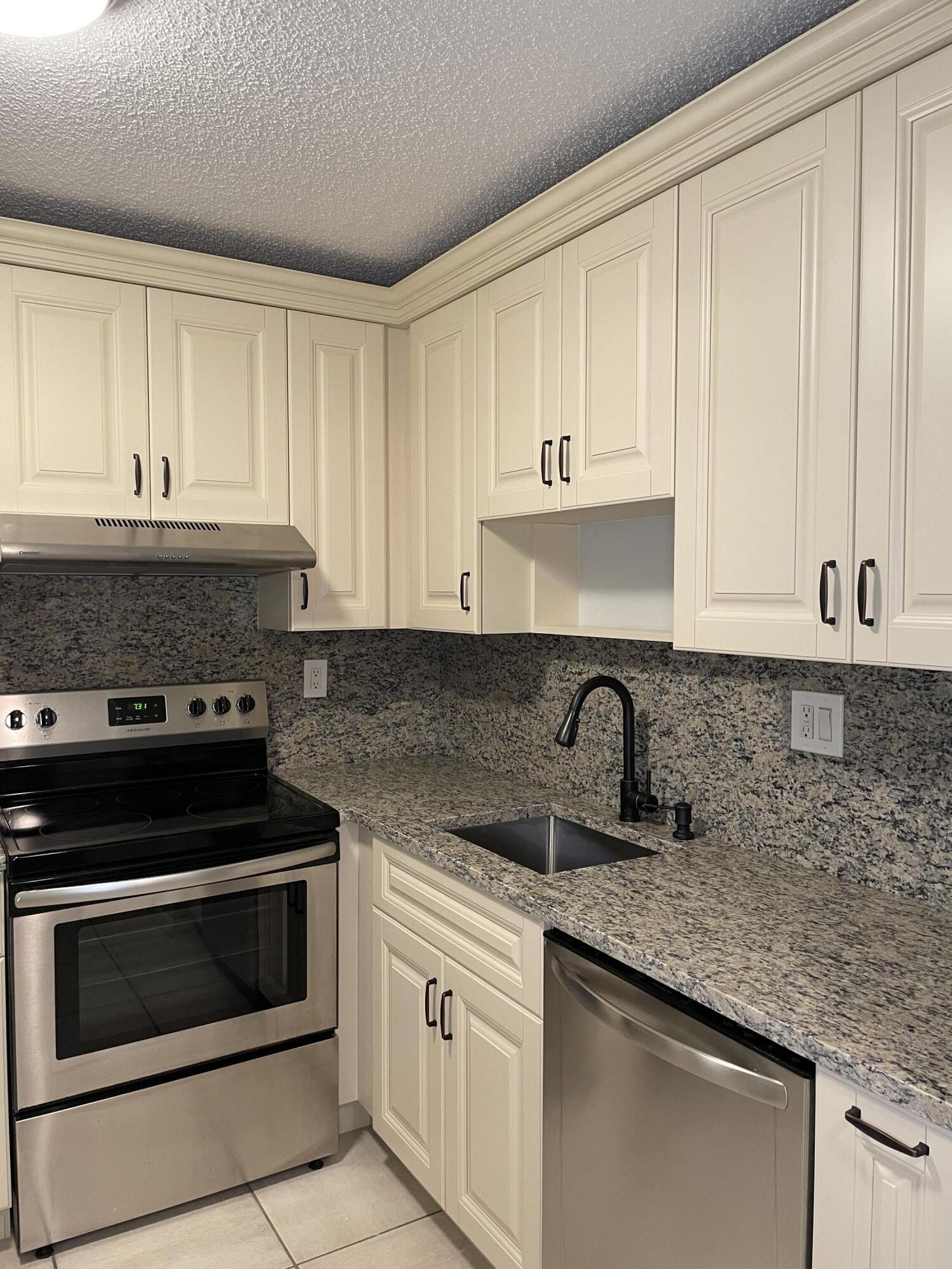 9440 Southwest 8th Street, Unit 217 Boca Raton, FL 33428 - Photo 6 of 28 a kitchen with granite countertop white cabinets and stainless steel appliances