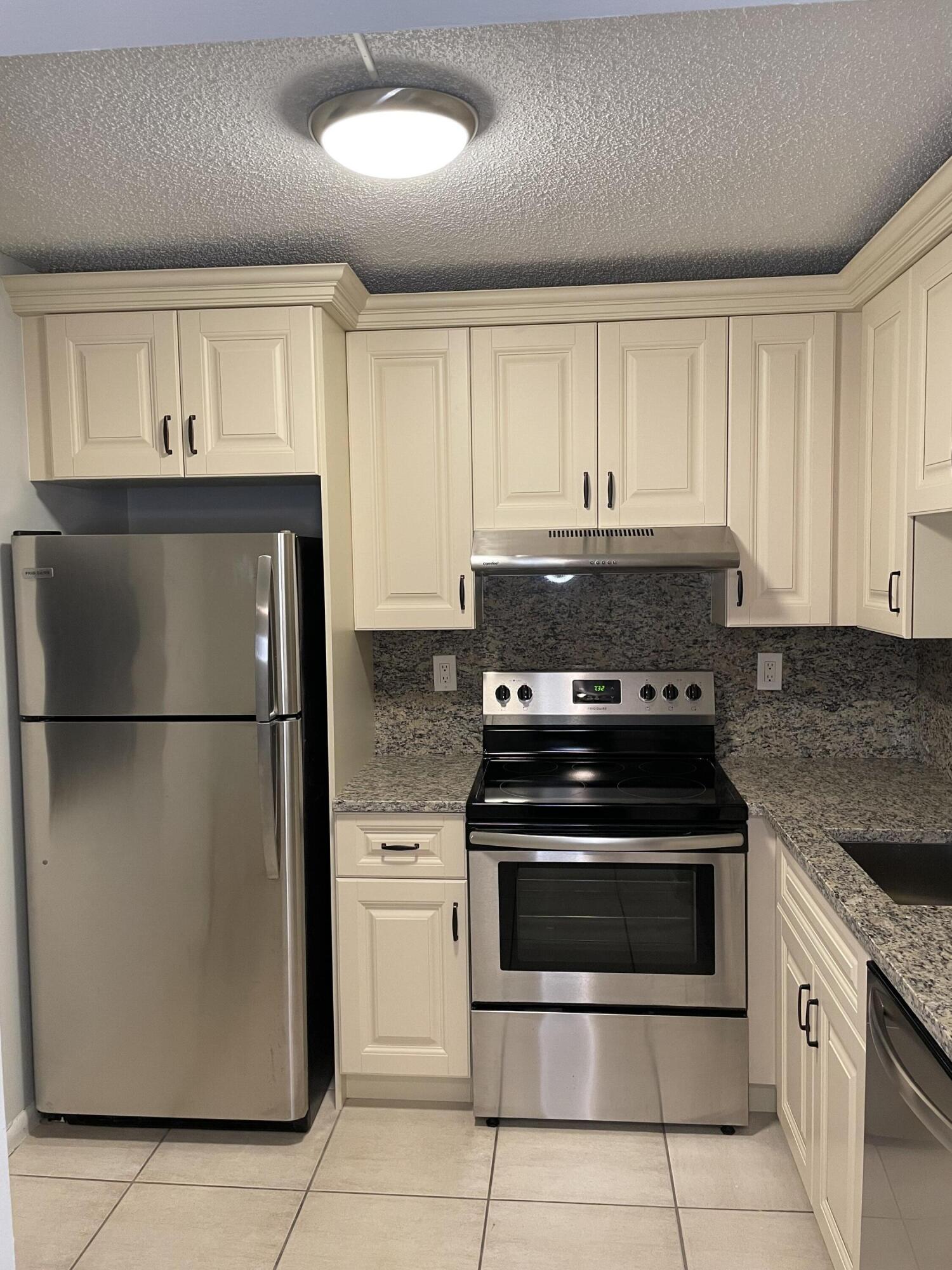 9440 Southwest 8th Street, Unit 217 Boca Raton, FL 33428 - Photo 7 of 28 a kitchen with granite countertop white cabinets and stainless steel appliances