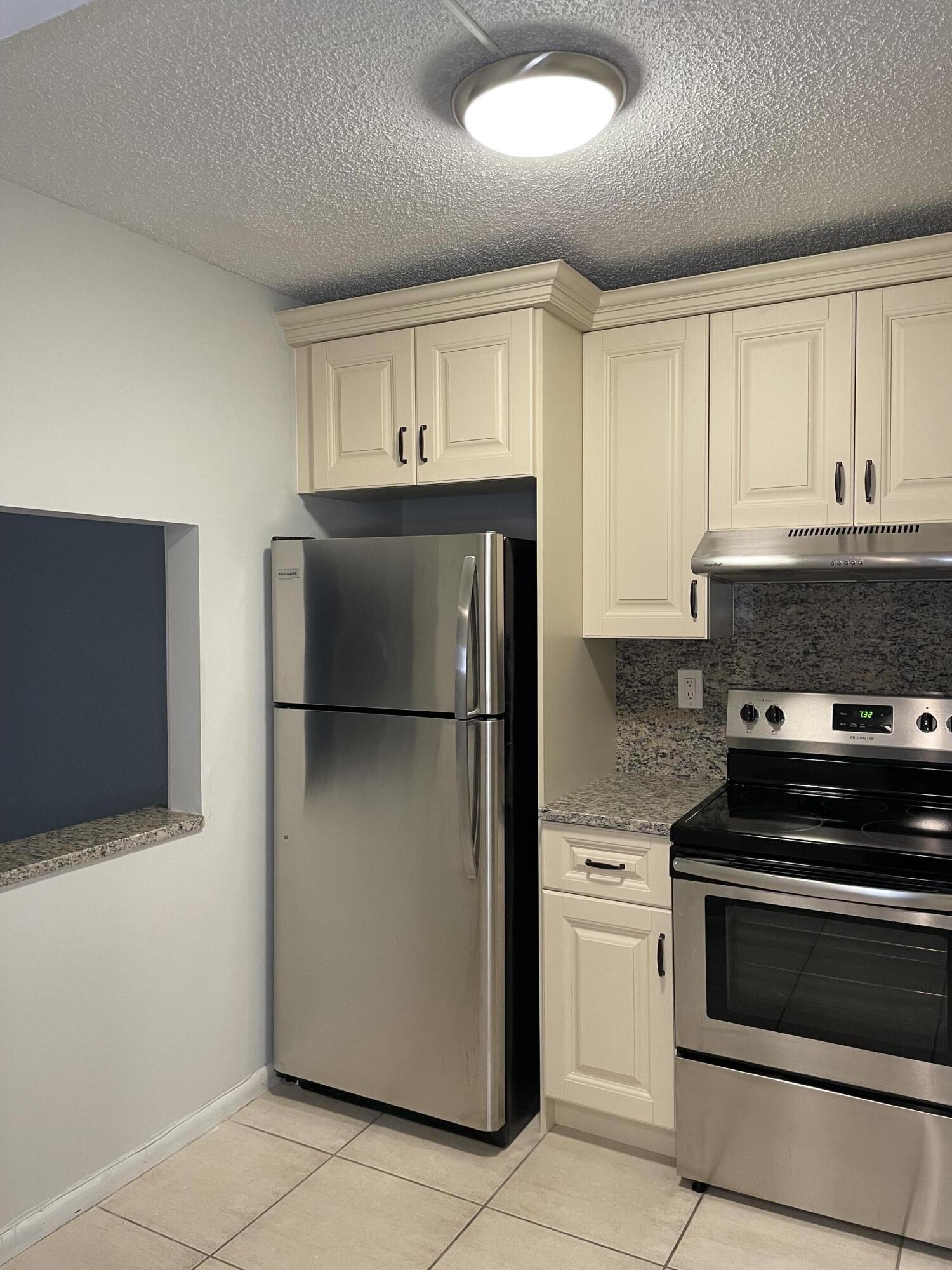 9440 Southwest 8th Street, Unit 217 Boca Raton, FL 33428 - Photo 8 of 28 a kitchen with a refrigerator stove and cabinets