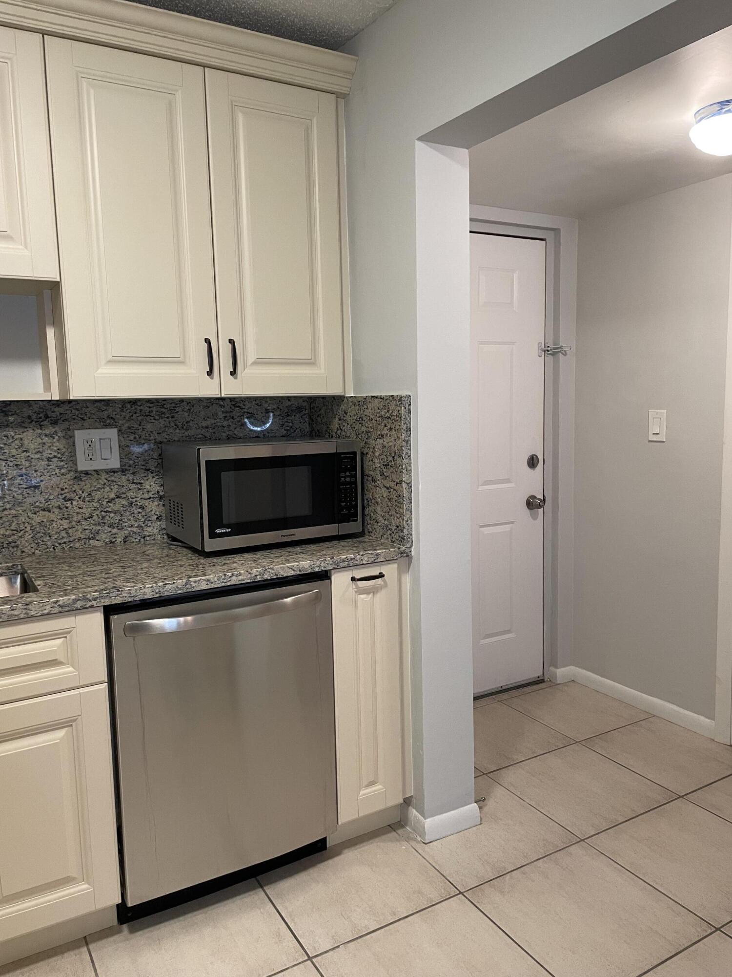 9440 Southwest 8th Street, Unit 217 Boca Raton, FL 33428 - Photo 10 of 28 a kitchen with granite countertop white cabinets and stainless steel appliances