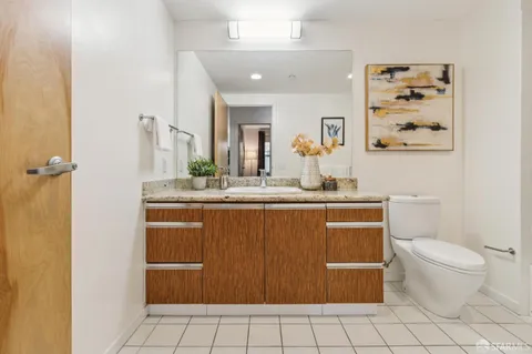 a bathroom with a granite countertop sink mirror vanity and toilet