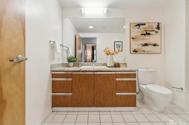 a bathroom with a granite countertop sink mirror vanity and toilet