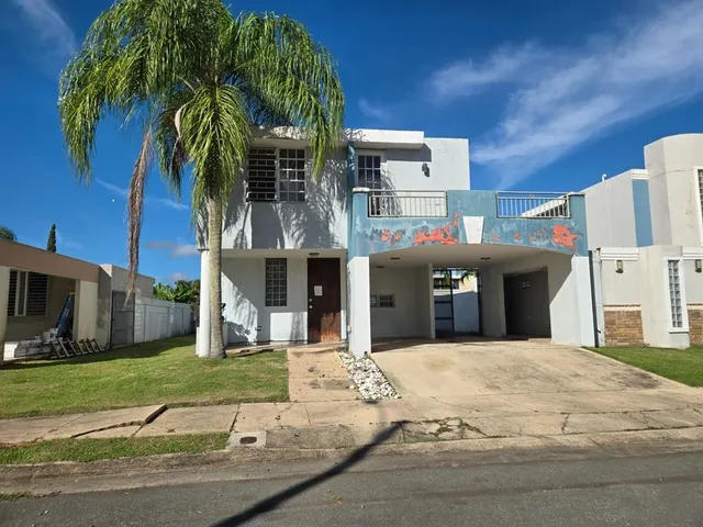 a view of a white house with a yard and palm trees