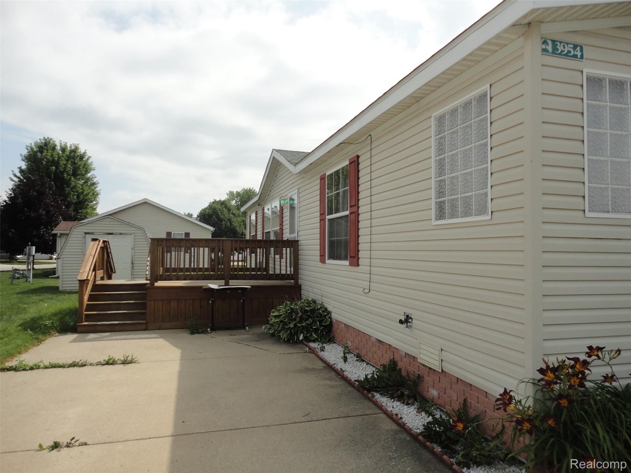 3954 Ryans Ridge Monroe, MI 48161 - Photo 26 of 28 Exterior featuring light-colored horizontal siding, a wood deck with stairs, and a detached shed