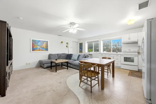 a view of a house with pool lawn chairs and a dining table and chairs under an umbrella