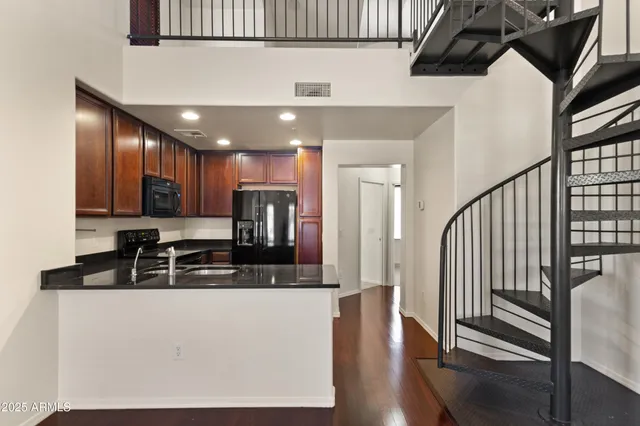 a kitchen with stainless steel appliances granite countertop a refrigerator a stove and a sink with wooden floor