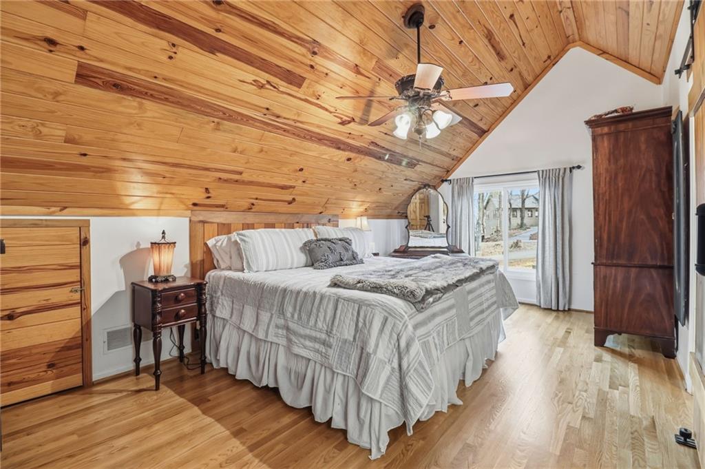 115 Chestnut Oak Point Big Canoe, GA 30143 - Photo 18 of 56 a spacious bedroom with a bed and wooden floor