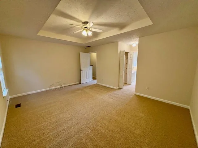 an empty room with a chandelier fan and windows