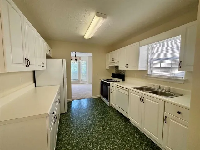 a kitchen with cabinets appliances a sink and a window