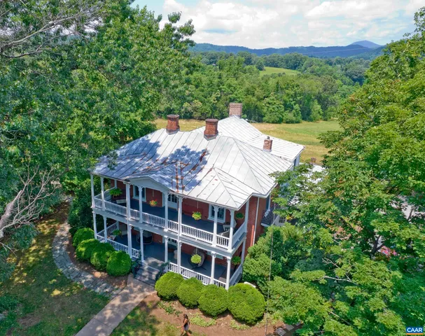 a backyard of a house with table and chairs plants and large trees