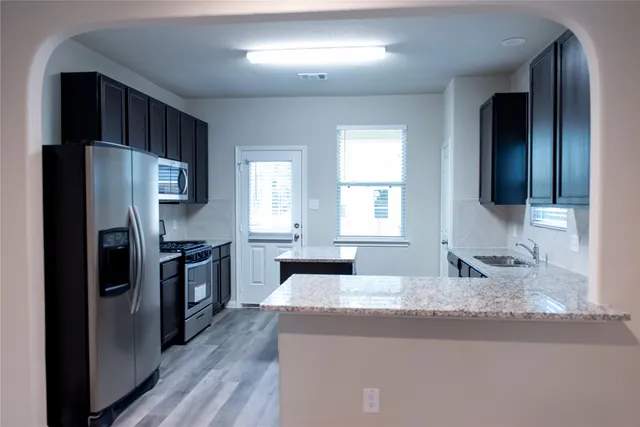 a kitchen with granite countertop kitchen island stainless steel appliances a refrigerator cabinets and sink