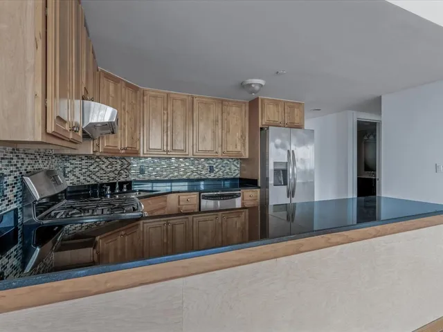 a kitchen with stainless steel appliances granite countertop a refrigerator and a stove