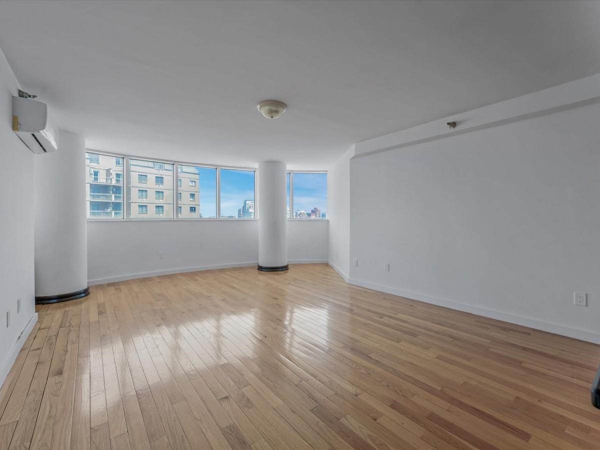 133-38 Sanford Avenue, Unit 11C Queens, NY 11355 - Photo 13 of 24 a view of empty room with wooden floor and fan