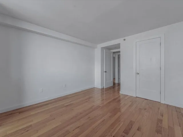a view of an empty room with wooden floor and closet