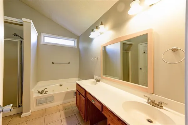 a bathroom with a tub a double vanity sink and mirror