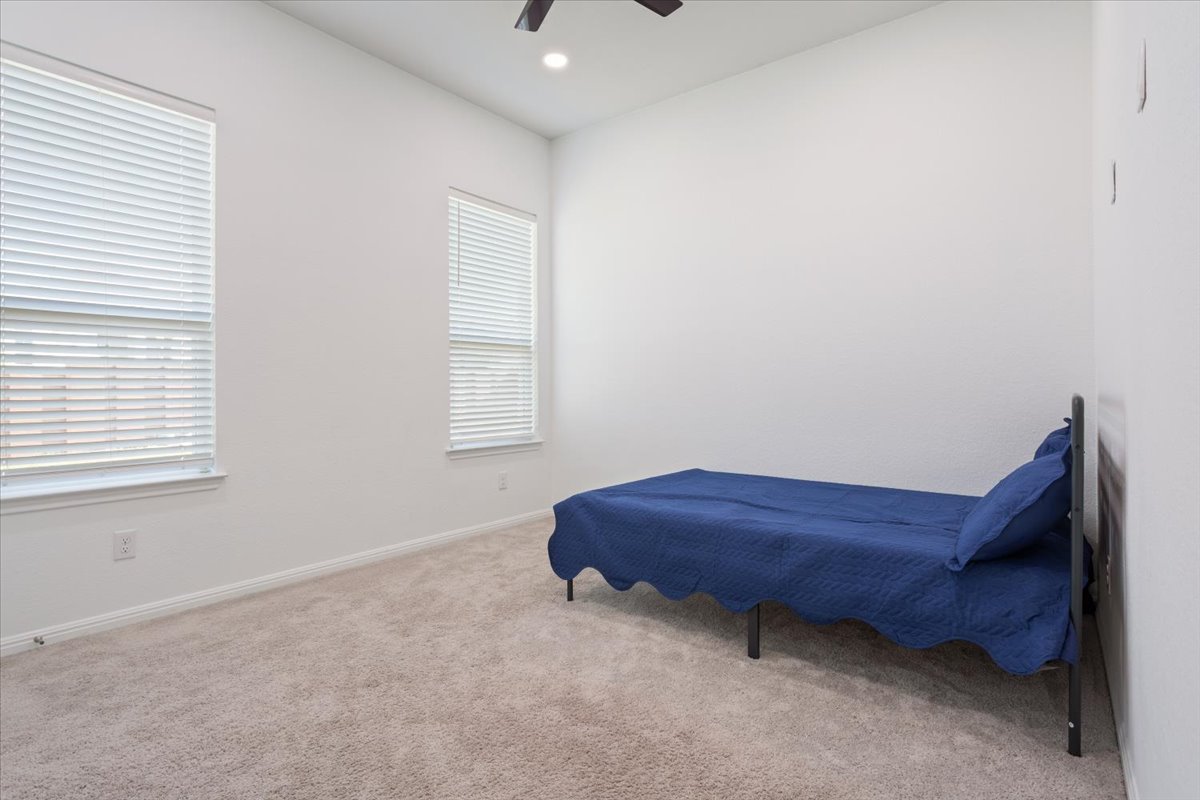 3625 Garrano Bend Leander, TX 78641 - Photo 20 of 38 A well-lit bedroom features plush carpet flooring and ample natural light from two windows.