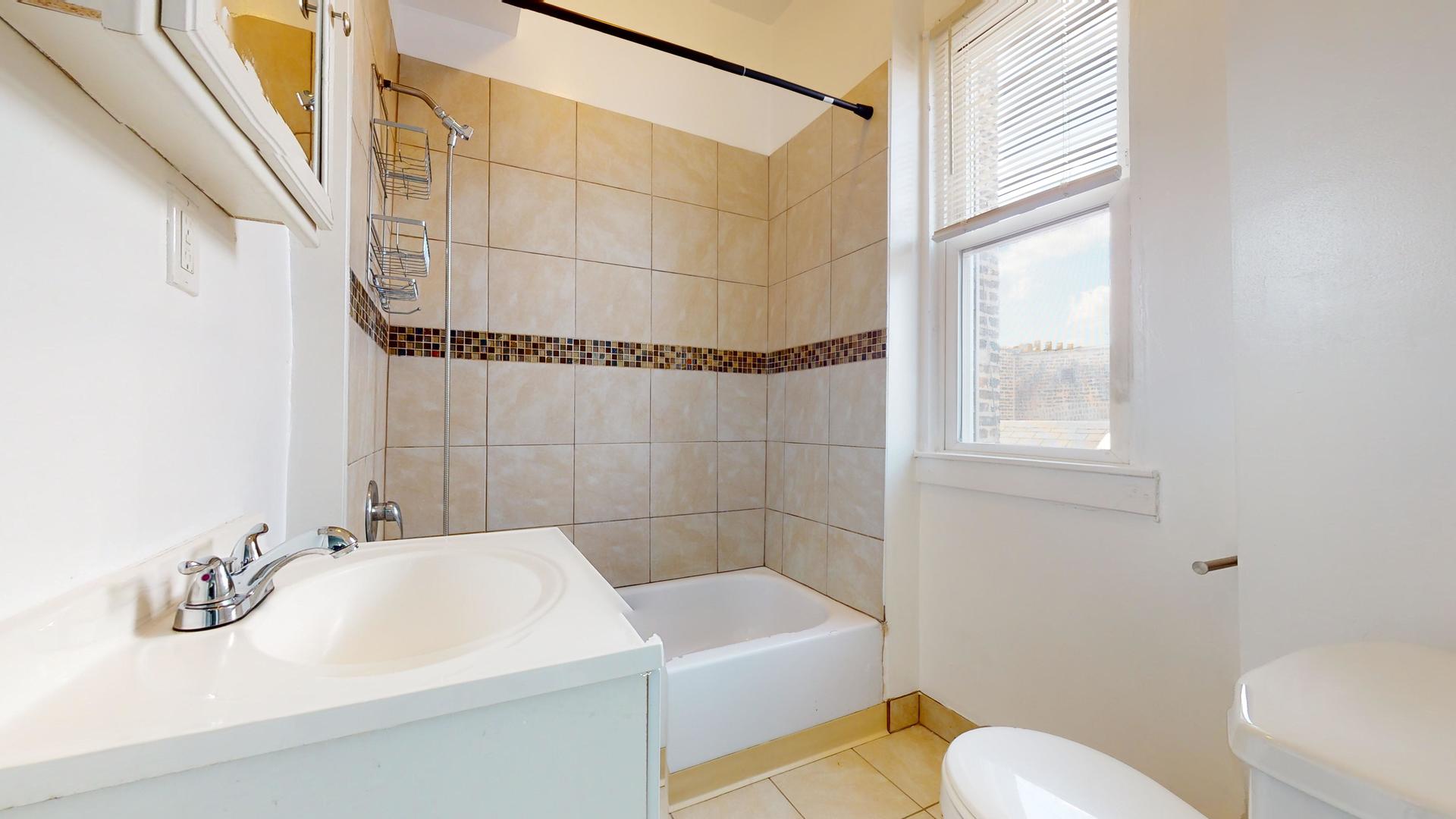 2700 West Cermak Road, Unit 2F Chicago, IL 60608 - Photo 12 of 16 a bathroom with a sink a toilet and shower