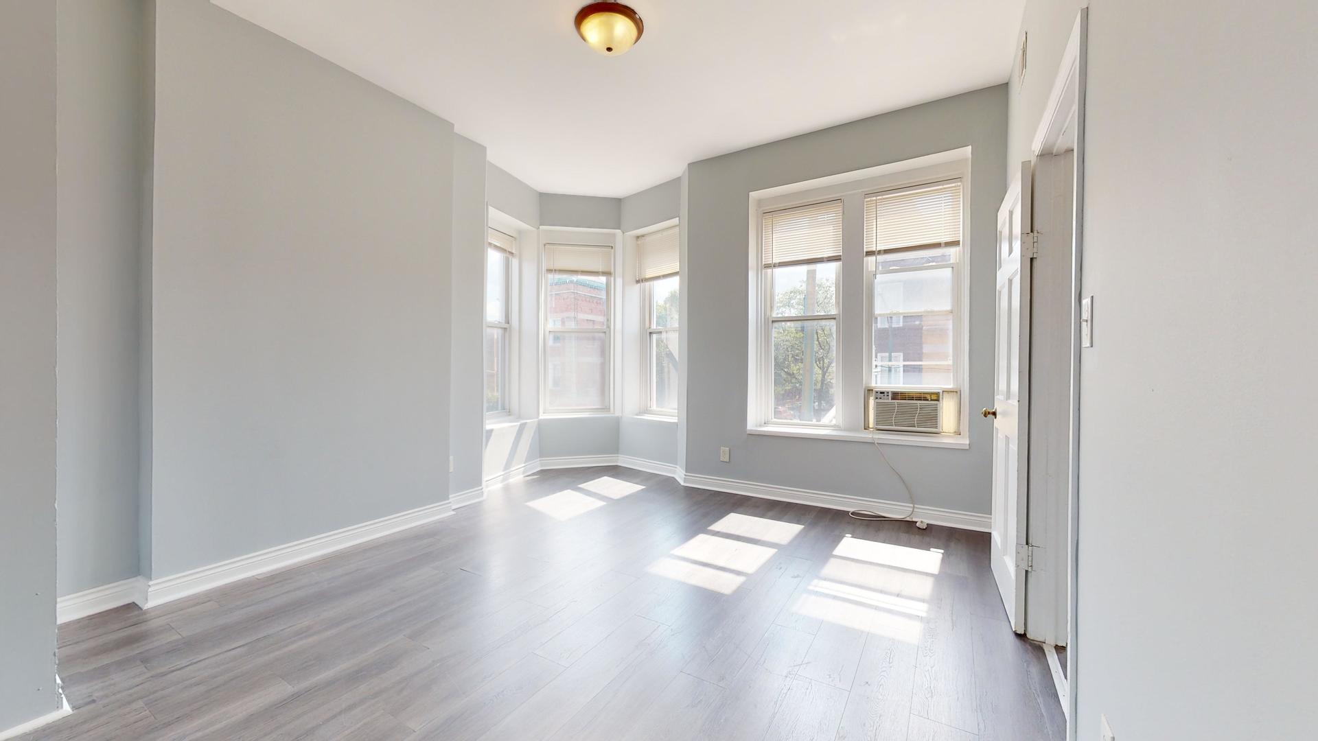 2700 West Cermak Road, Unit 2F Chicago, IL 60608 - Photo 3 of 16 an empty room with wooden floor and windows
