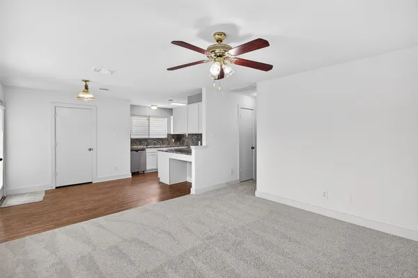 a view of an empty room with kitchen and a window
