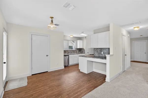 a open kitchen with white cabinets and wooden floor
