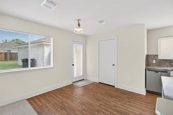 an empty room with wooden floor and windows