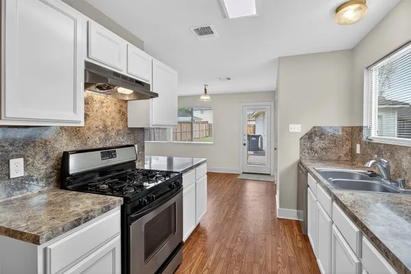 a kitchen with a sink stove top oven and cabinets