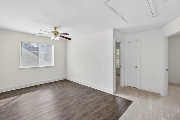 an empty room with wooden floor chandelier fan and windows