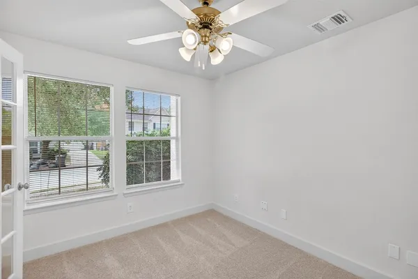 an empty room with windows and chandelier fan