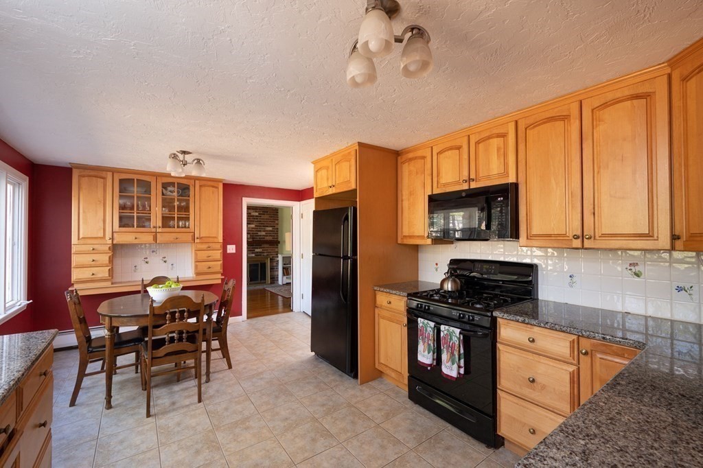 32 Old County Road Hingham, MA 02043 - Photo 10 of 38 a kitchen with stainless steel appliances granite countertop a stove top oven a sink a dining table and chairs with wooden floor