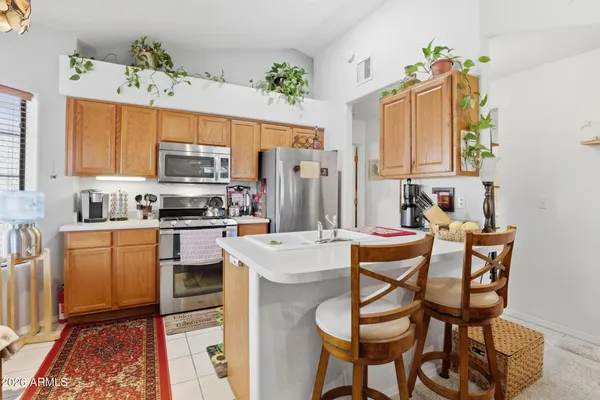 a kitchen with stainless steel appliances kitchen island granite countertop a refrigerator a stove a sink dishwasher and white cabinets with wooden floor