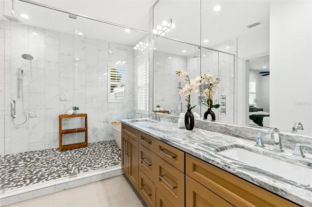 a bathroom with a double vanity sink a large mirror and shower