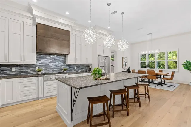 a kitchen with kitchen island granite countertop a table chairs sink and cabinets