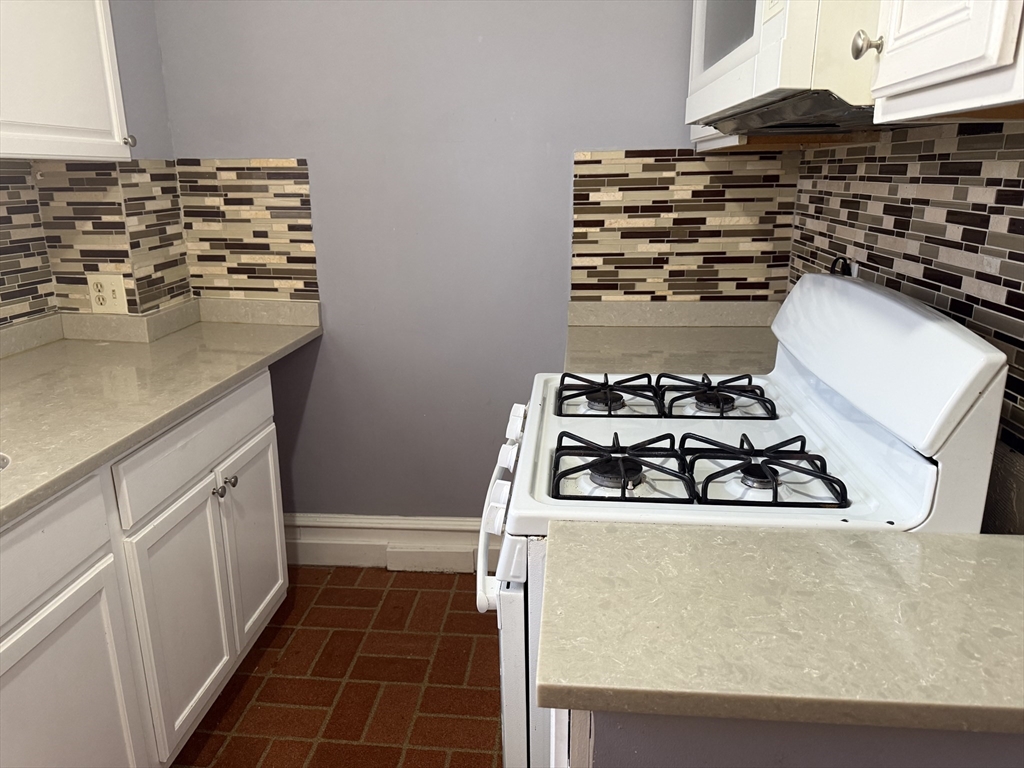 5-7 Stevens Street, Unit 1 Lawrence, MA 01843 - Photo 5 of 6 a kitchen with wooden cabinets and a stove top oven