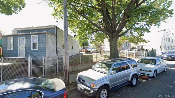 a car parked in front of a brick house with a large tree