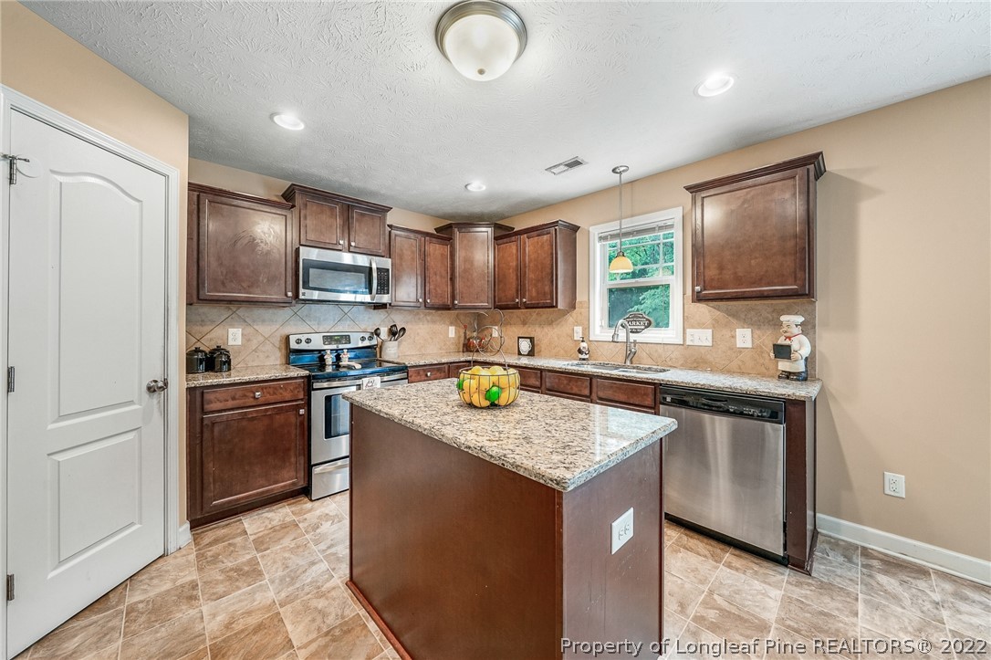 2673 Rockfish Road Raeford, NC 28376 - Photo 16 of 42 a kitchen with stainless steel appliances granite countertop a stove sink and refrigerator