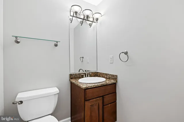 a bathroom with a granite countertop sink toilet and a mirror