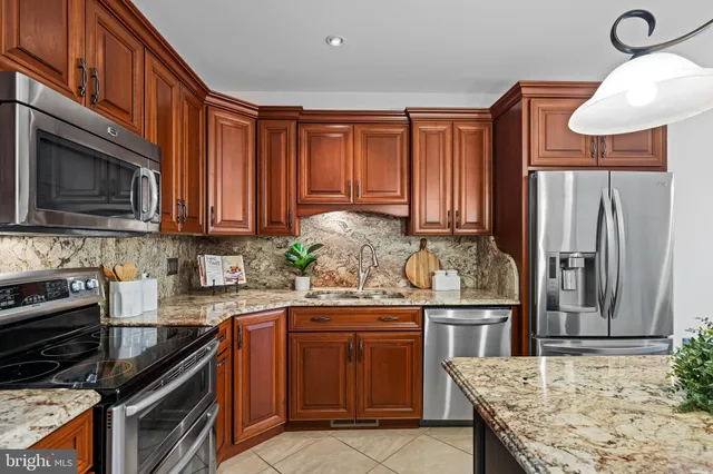 a kitchen with stainless steel appliances granite countertop a stove top oven a kitchen island a sink dishwasher and a microwave oven with cabinets