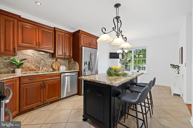 a kitchen with stainless steel appliances granite countertop wooden cabinets a table and chairs