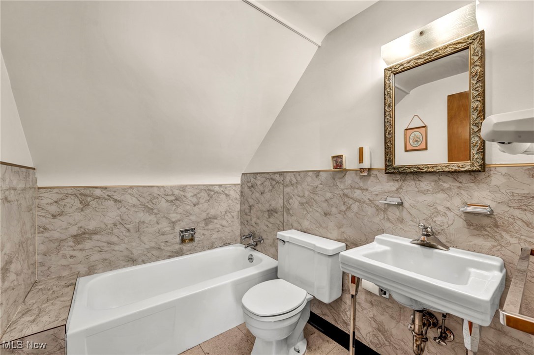 1711 Rush Road Wickliffe, OH 44092 - Photo 23 of 38 Full bath featuring a bath, vaulted ceiling, tile walls, and a wainscoted wall