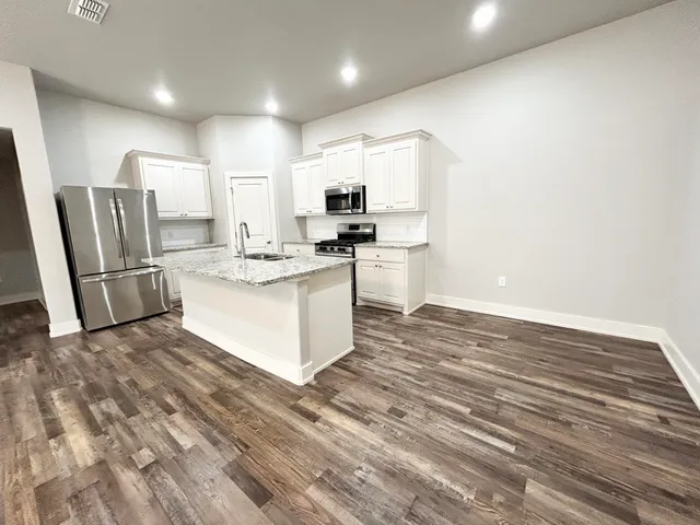 a kitchen with stainless steel appliances granite countertop a stove a refrigerator and a microwave