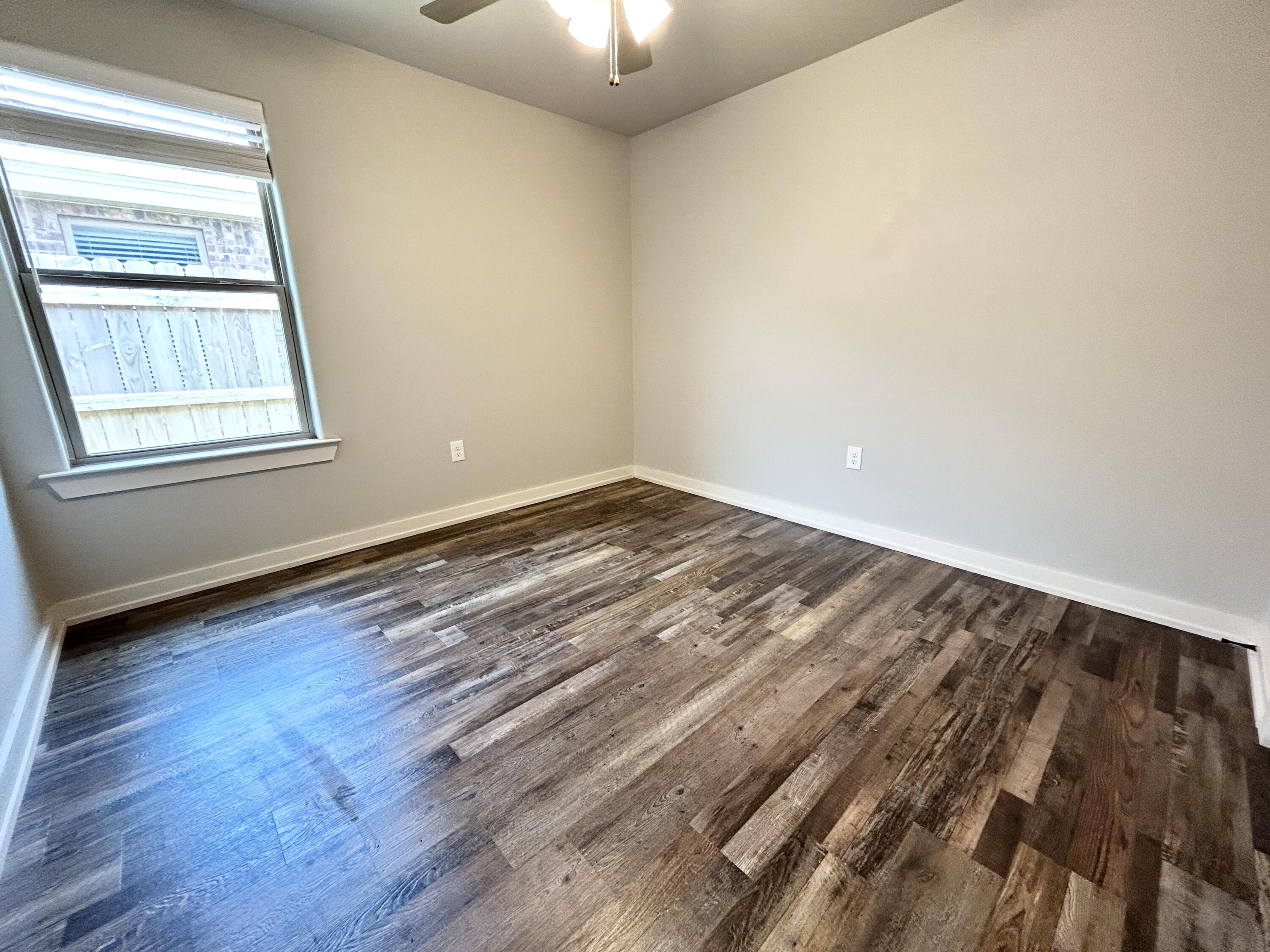 5512 122nd Street, Unit B Lubbock, TX 79424 - Photo 6 of 9 an empty room with wooden floor and windows